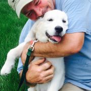 Happy owner embracing a white puppy, representing the secure and loving environment provided by a puppy electronic dog fence