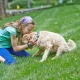 Young girl cuddling her dog in a safe garden protected by a DogFence system, showing dog fence safety for children